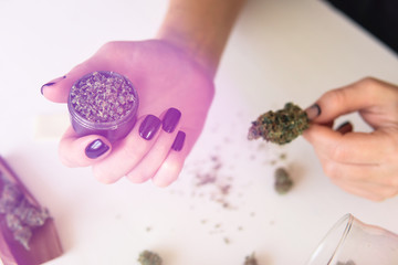 Close up of marijuana blunt with grinder. marijuana use concept. Woman rolling a cannabis blunt on...