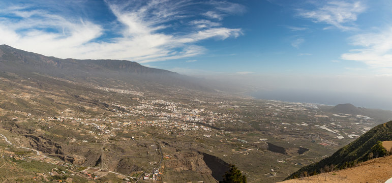 Aerial view of Guimar valley on a bright sunny day. The eastern end of the island disappears in a light haze in the background. Beautiful cirrus white clouds on the blue sky. Tenerife, Canary Islands