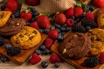 Chocolate biscuits on wooden platter with forest fruits close-up