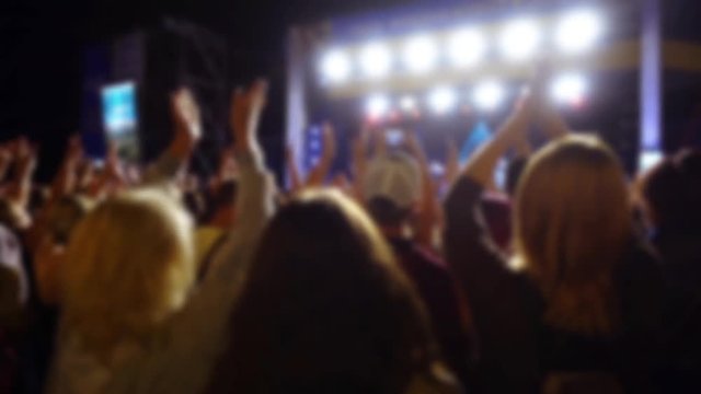 Concert on the stage. Crowd of people and musicians on the scene. Out of focus.