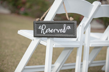 Reseved seating sign on white chair at outdoor wedding ceremony