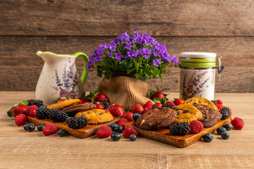 Wild berries with chocolate cookies, ceramic vessels and campanula