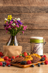 Glass vase with flowers, ceramic jar and wild berries