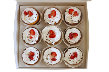 Close-up cupcakes with whipped eggs cream decorated fresh strawberry and chocolate balls in white paper box