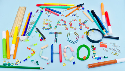 Back to school text made with colorful  school suplies against light blue background.