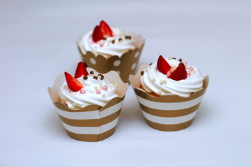 Close-up cupcakes with whipped eggs cream decorated fresh strawberry and chocolate balls on white background. Isolate