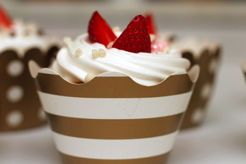 Close-up cupcakes with whipped eggs cream decorated fresh strawberry and chocolate balls on white background. Isolate