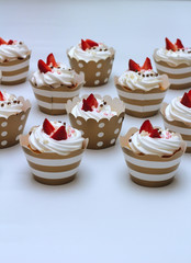 Close-up cupcakes with whipped eggs cream decorated fresh strawberry and chocolate balls on white background. Isolate