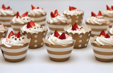 Close-up cupcakes with whipped eggs cream decorated fresh strawberry and chocolate balls on white background. Isolate