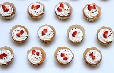 Close-up cupcakes with whipped eggs cream decorated fresh strawberry and chocolate balls on white background. Isolated top view