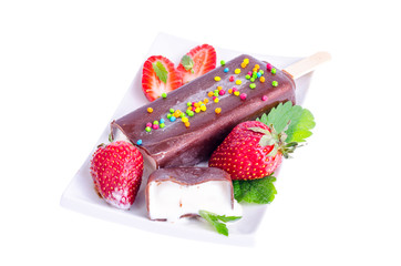 Ice cream in chocolate icing on stick with strawberries and mint