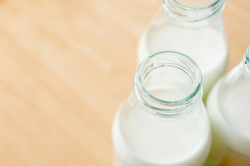 Fresh milk bottles without cap on wooden table near the window. A healthy drink concept. Copy space wallpaper.