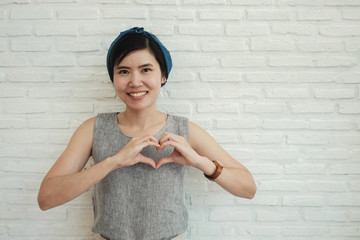 Happy Asian young woman making her hands in heart shape, heart health insurance, social...