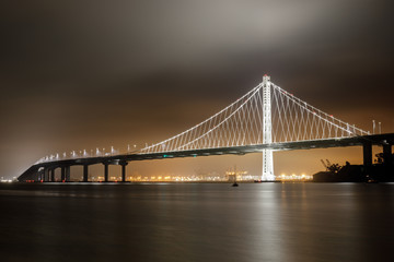 Fototapeta na wymiar Reflections of fog and water on the Bay Bridge eastern span on a summer night. Yerba Buena Island, San Francisco, California, USA.