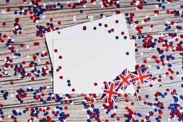 UK flag on wooden background with confetti and white paper sheets, layout, copy space. the concept of independence day, memory and sorrow