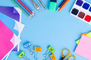 Back to school with schools accessories - paints, pencils, notebooks, scissors, markers, blue background. 