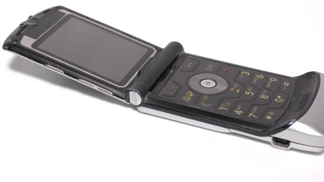 An old flip phone on white base and surface moving