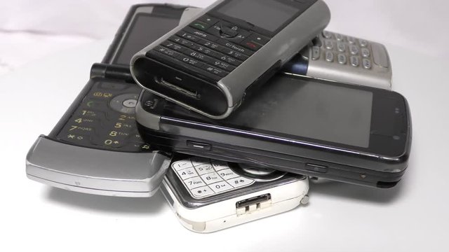 Old mobiles in stack and pile moving in circular motion on white