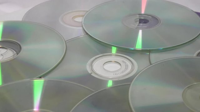 Old cds and dvds moving in circular motion on white surface