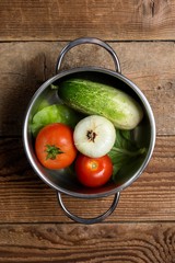 top view of cooking pot with vegetables. cucumbers with tomatoes.