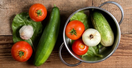 top view of cooking pot with vegetables. cucumbers with tomatoes.