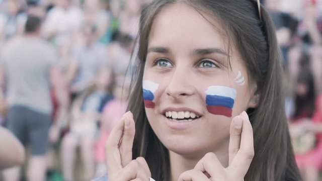 Russian Female football soccer fan cheering at match, supporting football team in fan zone.