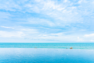Plakat Beautiful outdoor infinity swimming pool in hotel resort with sea ocean view and white cloud blue sky
