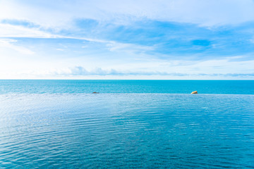 Fototapeta na wymiar Beautiful outdoor infinity swimming pool in hotel resort with sea ocean view and white cloud blue sky