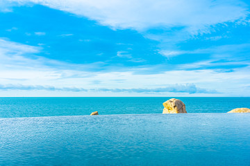 Plakat Beautiful outdoor infinity swimming pool in hotel resort with sea ocean view and white cloud blue sky