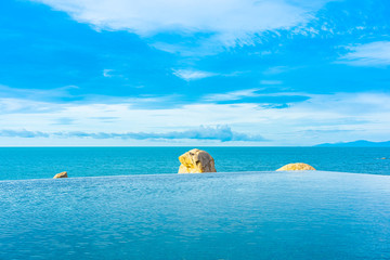 Plakat Beautiful outdoor infinity swimming pool in hotel resort with sea ocean view and white cloud blue sky