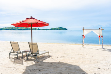 Beautiful outdoor tropical beach sea ocean with umbrella chair and lounge deck around there on white cloud blue sky