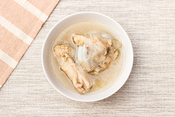 Bowl of pork bone soup with herbs on gray table mat 