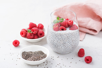 Healthy vanilla chia pudding in a glass with fresh raspberries .