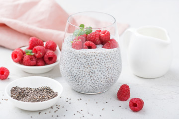 Healthy vanilla chia pudding in a glass with fresh raspberries .