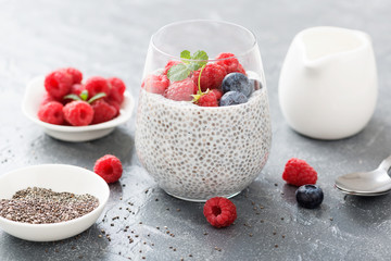 Healthy vanilla chia pudding in a glass with fresh raspberries .