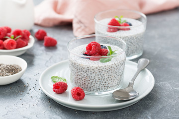 Healthy vanilla chia pudding in a glass with fresh raspberries .