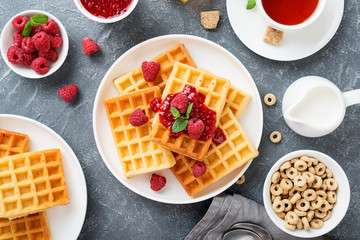 Traditional belgian waffles with fresh raspberry and jam on gray background.