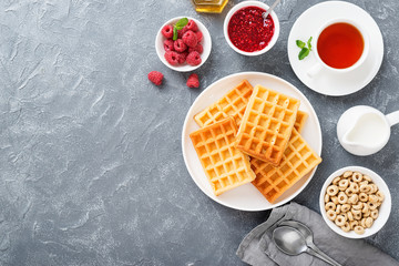 Traditional belgian waffles with fresh raspberry and jam on gray background.