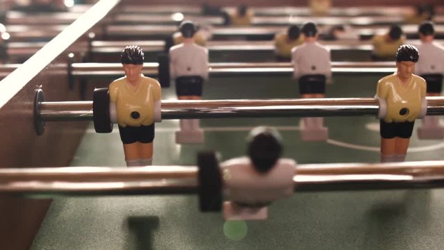 People playing in table football or kicker with miniature players. Table football game with yellow and white players. Employees playing table soccer indoor-game in the office during break time.