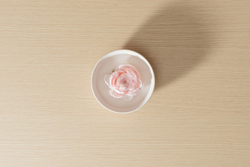 Flower isolated on the white plate on wood background