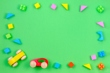 Baby kid toy background. Colorful wooden cubes and two cars on green background