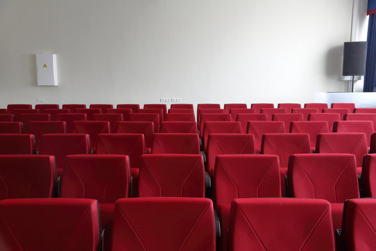 Rows of red seats in an empty room for presentations, press conferences and seminars