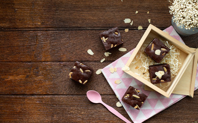 Piece of brownie almond in wood box decorate with pink spoon and dry flower on wood table.