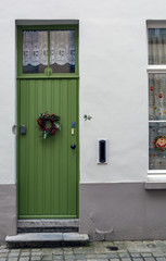Vintage green front door decorated with Christmas wreath shot in Bruges, Belgium. Old green door with window at the top.