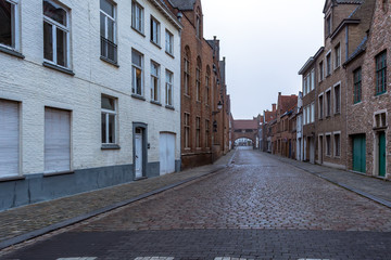 Picturesque old street of Bruges with traditional medieval houses and cobbled road in slight...