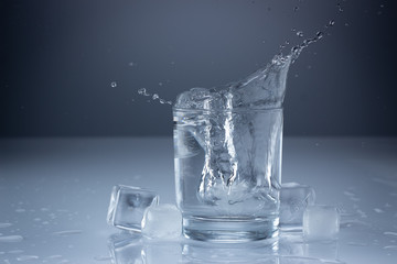 Pouring water into glass on blue background close up