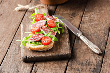 Sandwich with green salad on wooden table