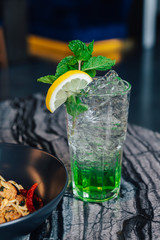 Iced Apple Soda with sliced lemon and mint leaves in drinking glass on marble top table.
