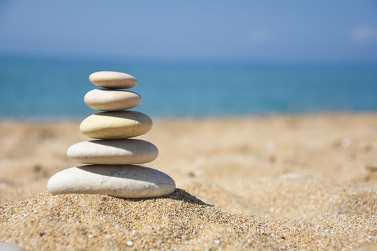 Balanced stone pyramid on sand on beach. Zen rock, concept of balance and harmony