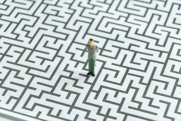 Miniature people: Businessman standing on start point of maze